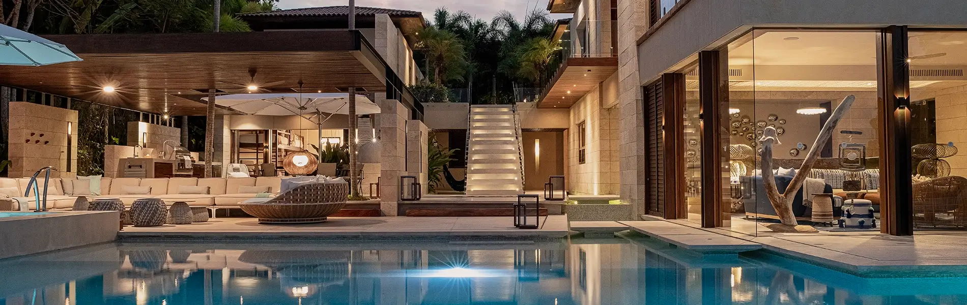 Modern house with glass walls, a pool, and an outdoor area.