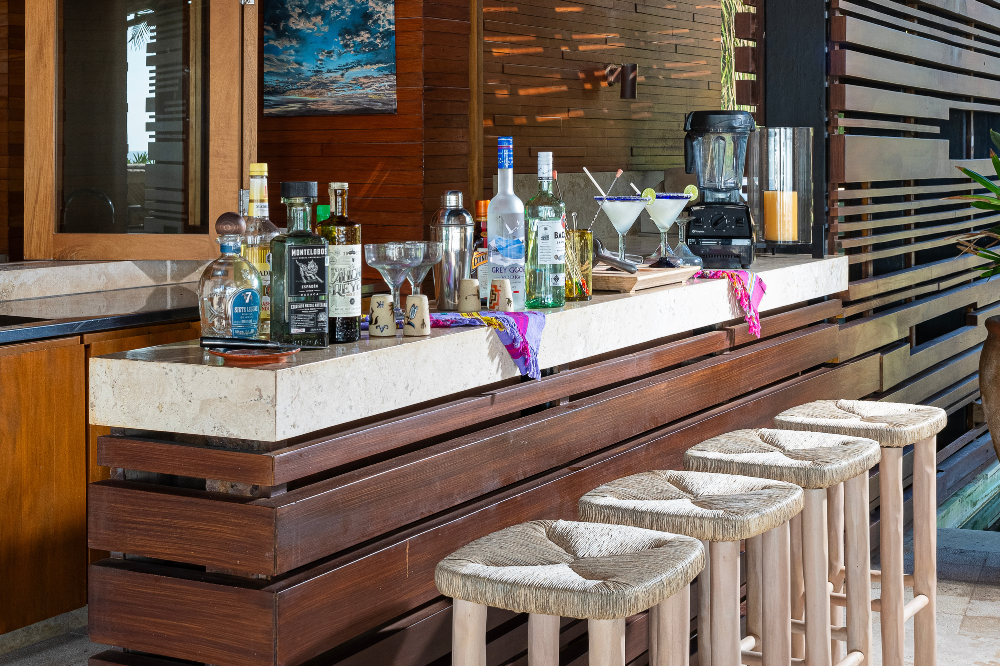 A professional bartender crafting signature cocktails for guests at Villa Samba, highlighting the luxury of fully staffed villas in Mexico.